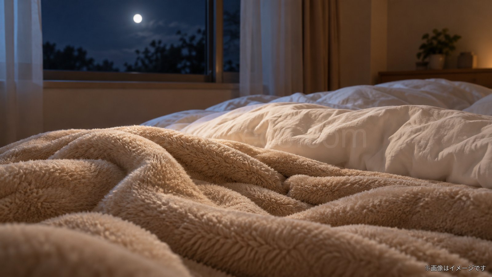 冬の夜の寝室でベージュの毛布と布団が重なっているイメージ